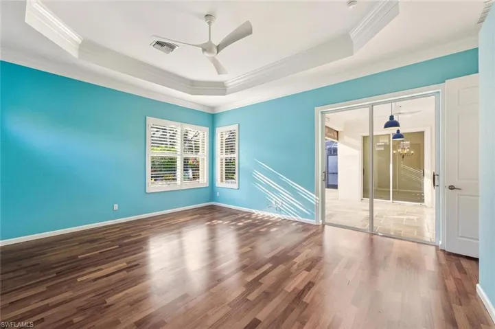 Unfurnished room featuring dark wood finished floors, a ceiling fan, ornamental molding, and a raised ceiling