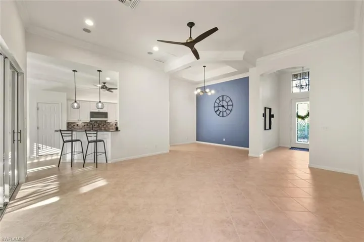 Unfurnished living room with a ceiling fan, ornamental molding, a chandelier, and recessed lighting