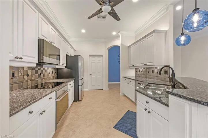 Kitchen featuring white cabinetry, tasteful backsplash, dark stone countertops, crown molding, and recessed lighting
