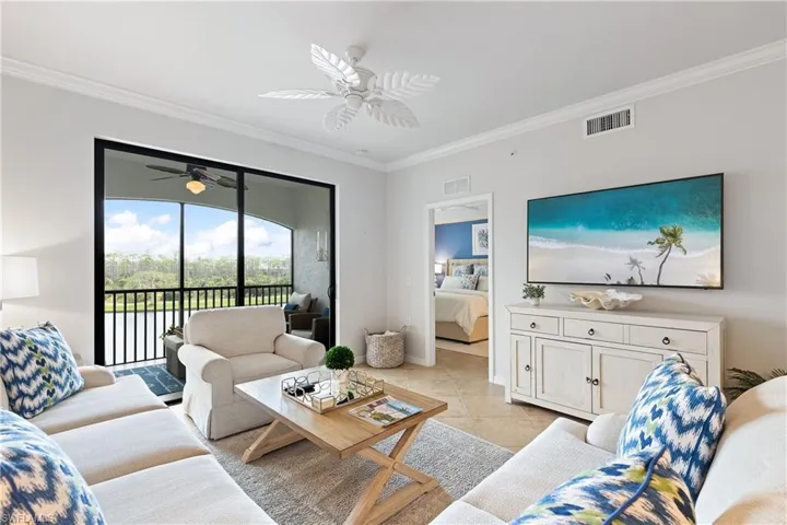 Tiled living room featuring ceiling fan and ornamental molding