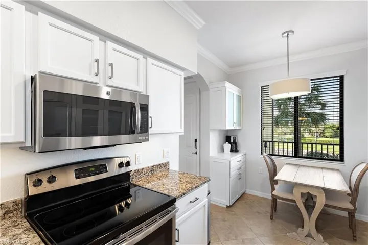 Kitchen with dark stone countertops, white cabinetry, and stainless steel appliances