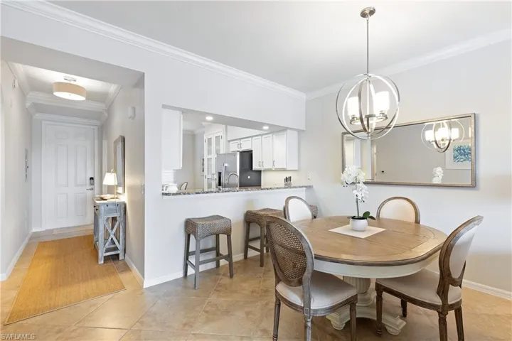 Tiled dining space featuring an inviting chandelier and crown molding