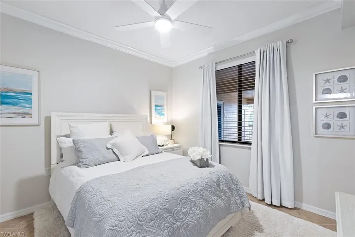 Bedroom featuring ceiling fan, light tile patterned floors, and crown molding