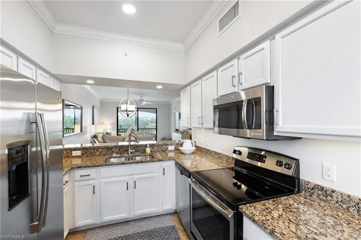 Kitchen with white cabinets, stainless steel appliances, ornamental molding, and sink