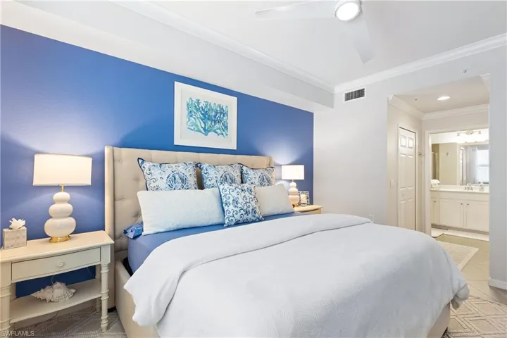 Tiled bedroom featuring ensuite bathroom, ceiling fan, and crown molding
