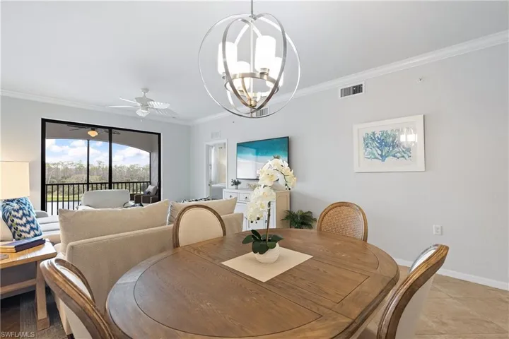 Dining area featuring ceiling fan with notable chandelier, ornamental molding, and light tile patterned floors