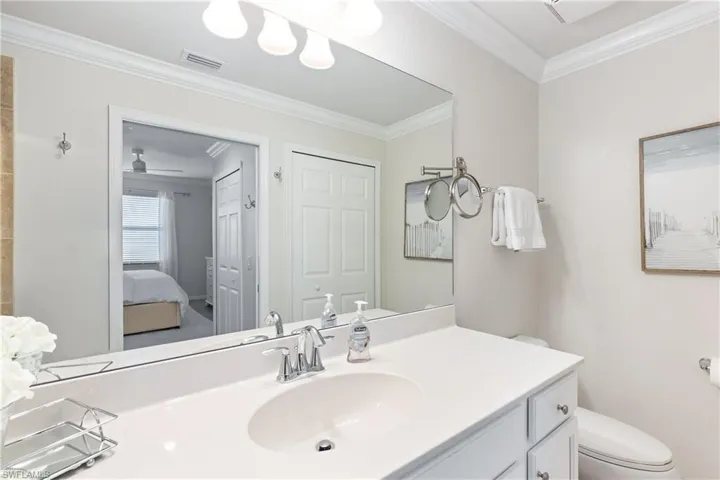 Bathroom featuring vanity, toilet, ceiling fan, and ornamental molding