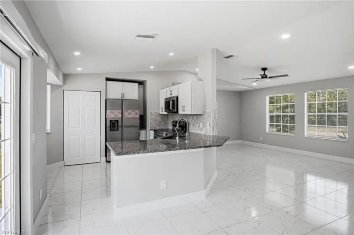 Spacious living area featuring white tile flooring, recessed lighting, and a contemporary ceiling fan