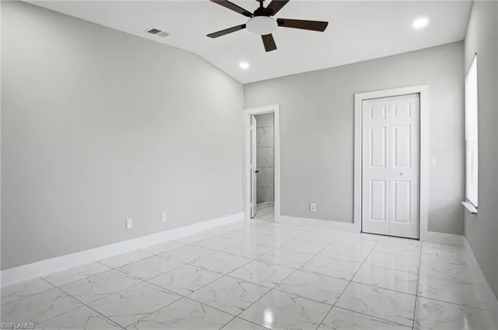 Spacious interior with large format white tile flooring, vaulted ceiling, and recessed lighting