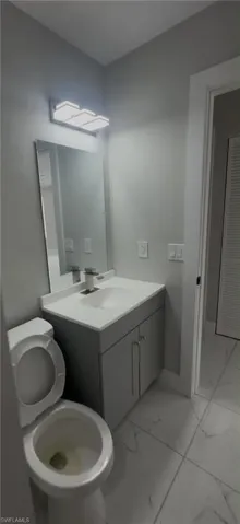 Bathroom featuring a gray vanity with double cabinet doors, a white countertop with an integrated sink, a rectangular mirror, and a three-light vanity fixture