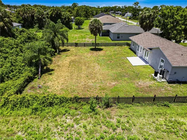 Spacious parcel featuring a partially fenced perimeter, mature palm trees, and a flat, grassed area