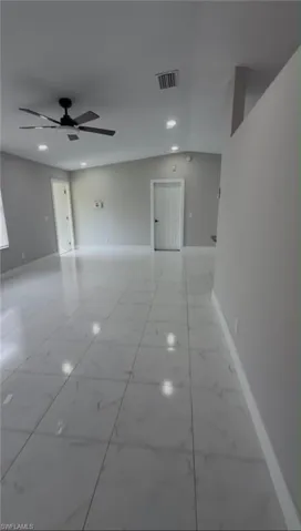 Spacious room featuring large format tile flooring, a vaulted ceiling, recessed lighting, a ceiling fan with black blades, and light gray wall finishes