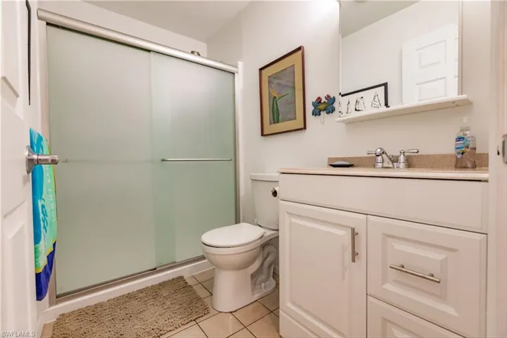 Bathroom with tile patterned floors, a shower with door, vanity, and toilet