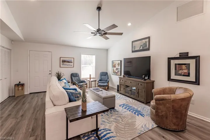 Living room featuring dark hardwood / wood-style floors, ceiling fan, and lofted ceiling
