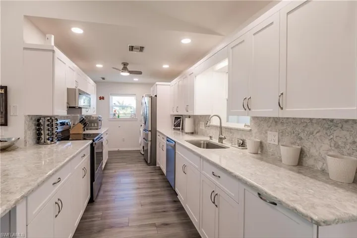 Kitchen featuring sink, white cabinets, dark hardwood / wood-style floors, and appliances with stainless steel finishes