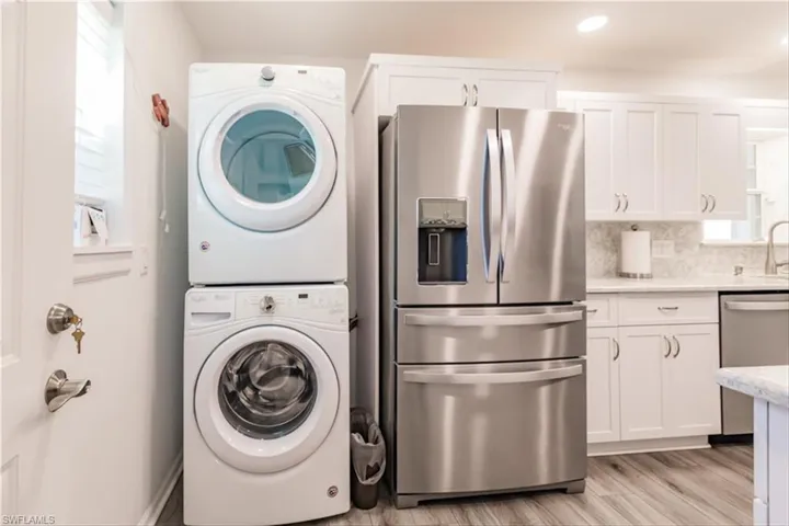 Laundry area with light wood-type flooring and stacked washer / dryer