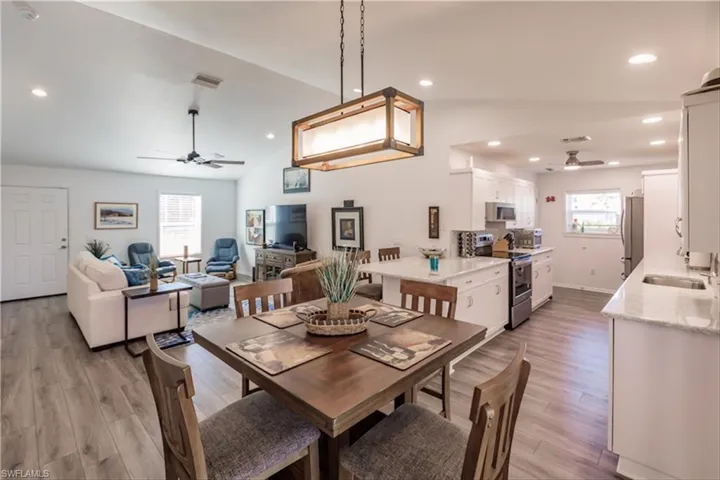 Dining space with sink, light hardwood / wood-style floors, and vaulted ceiling