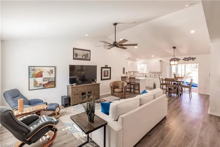 Living room featuring wood-type flooring, ceiling fan, and lofted ceiling