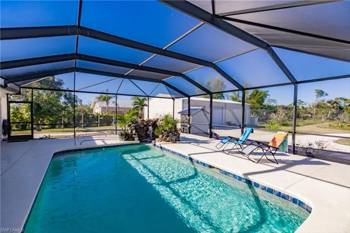 View of pool featuring a lanai, a patio area, and a storage shed