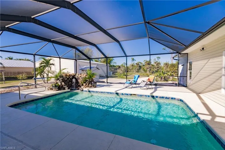 View of pool with glass enclosure and a patio area