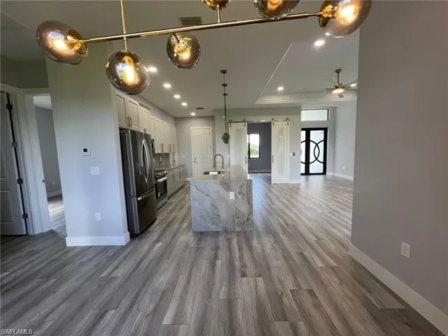 Kitchen with visible vents, a barn door, appliances with stainless steel finishes, white cabinetry, and a sink