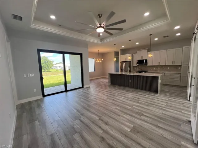 Kitchen with a raised ceiling, appliances with stainless steel finishes, open floor plan, a ceiling fan, and recessed lighting