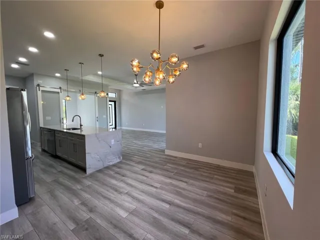 Kitchen with appliances with stainless steel finishes, open floor plan, wood finished floors, recessed lighting, and a chandelier