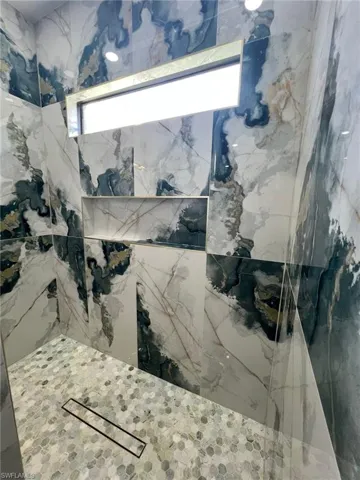 Bathroom with a marble finish shower and healthy amount of natural light