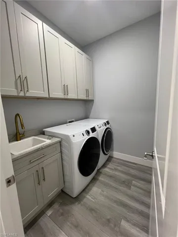 Laundry room featuring cabinet space, independent washer and dryer, and light wood-style flooring