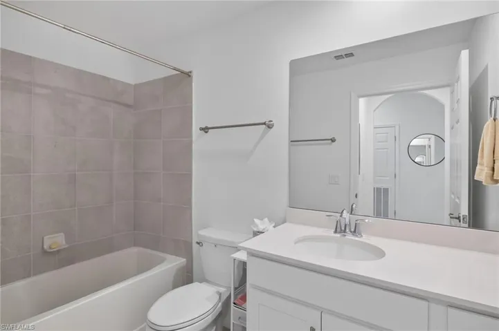 Full bathroom with vanity, tiled shower / bath combo, and toilet