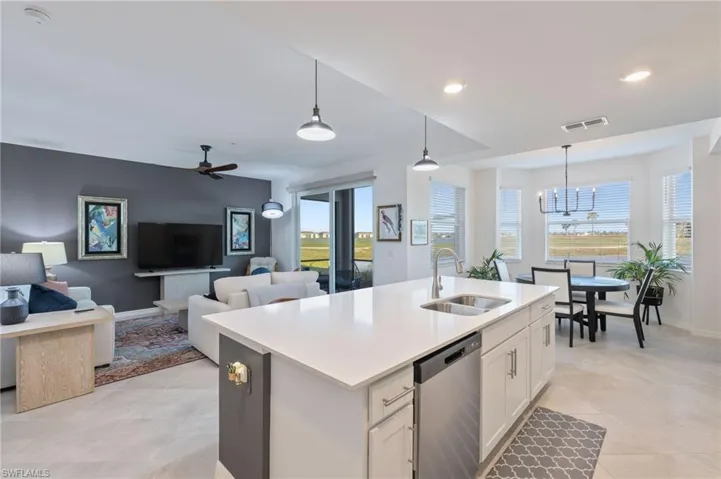 Kitchen featuring pendant lighting, sink, ceiling fan with notable chandelier, white cabinets, and stainless steel dishwasher