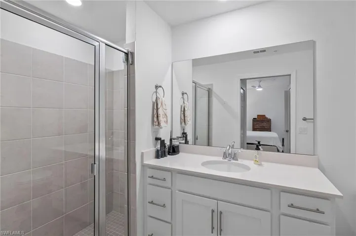 Bathroom with ceiling fan, an enclosed shower, and vanity
