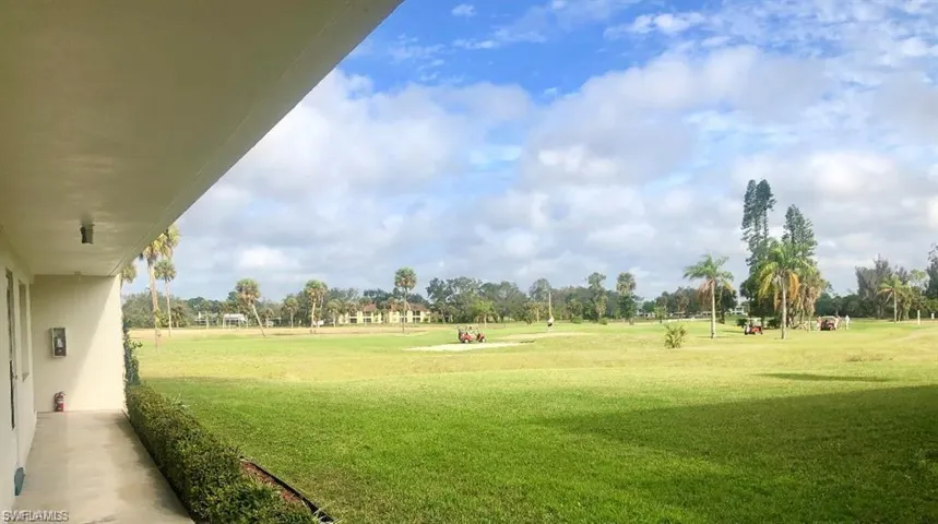 View of property's community with view of golf course, a lawn, and view of wooded area