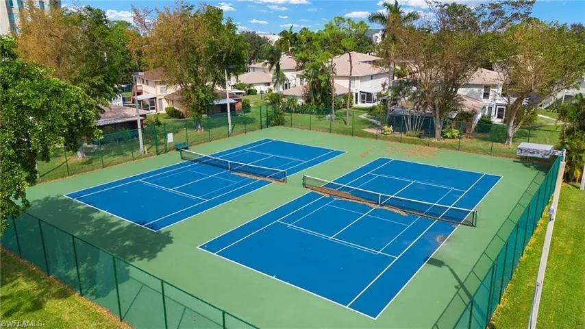 View of tennis court with a residential view