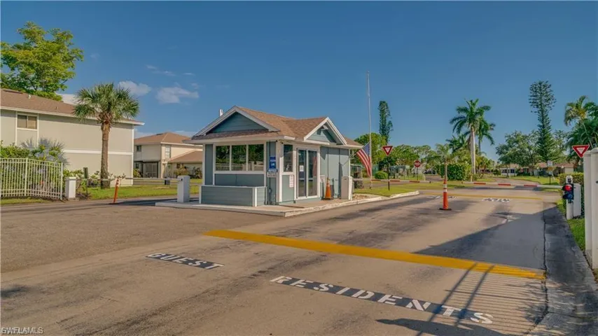 View of asphalt street with a speed bump, traffic signs, a gated entry, and curbs