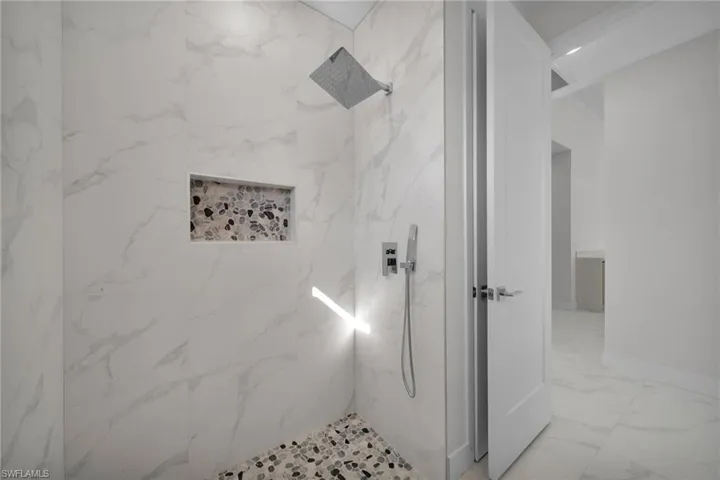 Full bathroom featuring a marble finish shower and light marble finish flooring