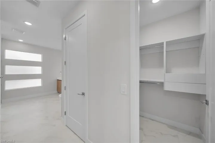 Hall featuring light marble finish floors and recessed lighting