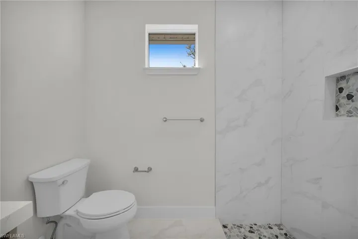 Full bath with toilet and a marble finish shower