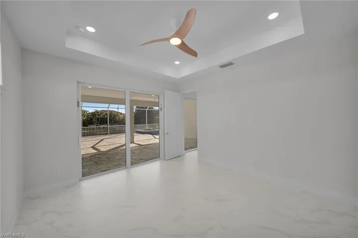 Spare room featuring ceiling fan, recessed lighting, light marble finish flooring, and a tray ceiling