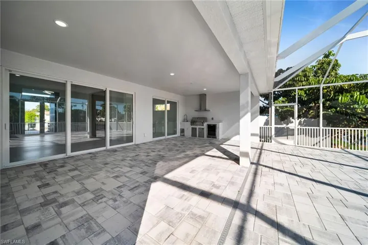 View of patio with a lanai, a sunroom, grilling area, and wine cooler