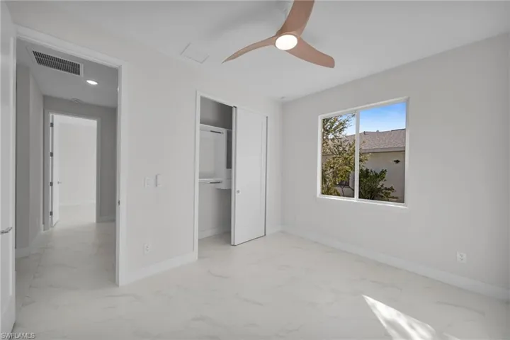 Unfurnished bedroom with light marble finish flooring, a closet, a ceiling fan, and recessed lighting