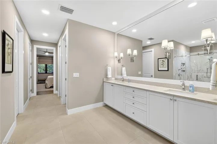 Full bathroom featuring two connected his and hers walk in closets with custom built-ins, recessed lighting, and tile patterned flooring