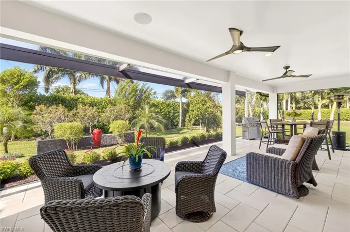 Expansive picture window screened extended lanai with outdoor dining area, firepit, and grill both with built in propane outlets, and two ceiling fans