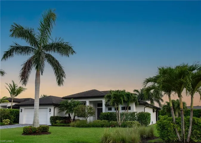 View of front of home at sunrise featuring attached two car extended garage, landscaped yard, stucco siding, and brick paved driveway