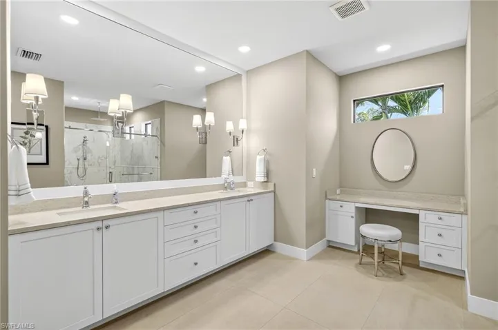Owners Suite bathroom featuring a llarge walk in tiled shower, double vanity, plus additional make-up vanity, tile patterned flooring, and recessed lighting