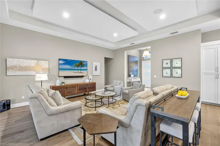 Living area great room with a custom tray/drop ceiling, light engineered wood flooring, and recessed lighting