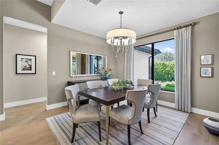 Dining room featuring a designer chandelier and light wood-style flooring and enlarged custom window and treatments