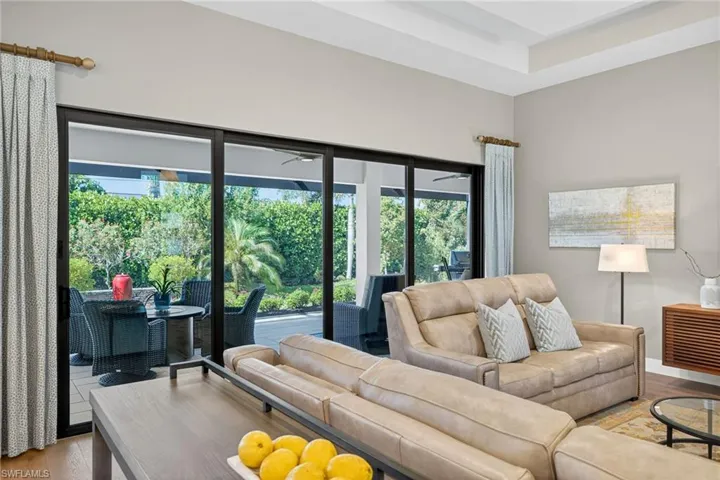 Living room with light wood finished floors, beautiful amount of natural light from the southern exposure, and 16' sliding glass pocketing doors open to the screened lanai.