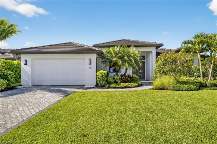 Ranch-style home featuring two-car extended attached garage, landscaped lawn, brick paved driveway, stucco siding, and concrete tile roof