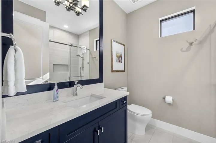 Guest bathroom with vanity, walk-in shower  and tile floors